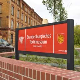 Willkommens-Standschild, montiert mit Bodenfreiheit im Garten hinter einer Mauer Willkommens-Standschild, montiert mit Bodenfreiheit im Garten hinter einer Mauer